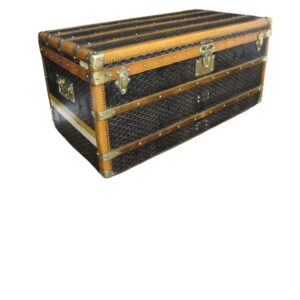 Front view of an antique Goyard steamer trunk coffee table from the 1920s, showing the iconic chevron canvas, brass lock, and honey-colored lozine trim.